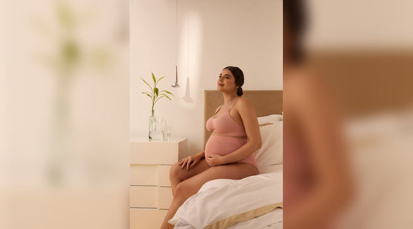 Mulher sentada na cama e que se encontra na fase do pó-parto.